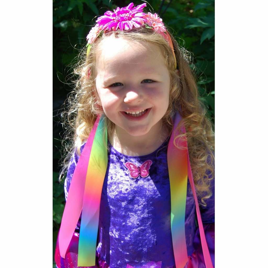 girl wearing rainbow ribbon headband and purple fairy wings